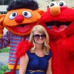 Girl standing in front of Ernie and the Grobie of Sesame Street