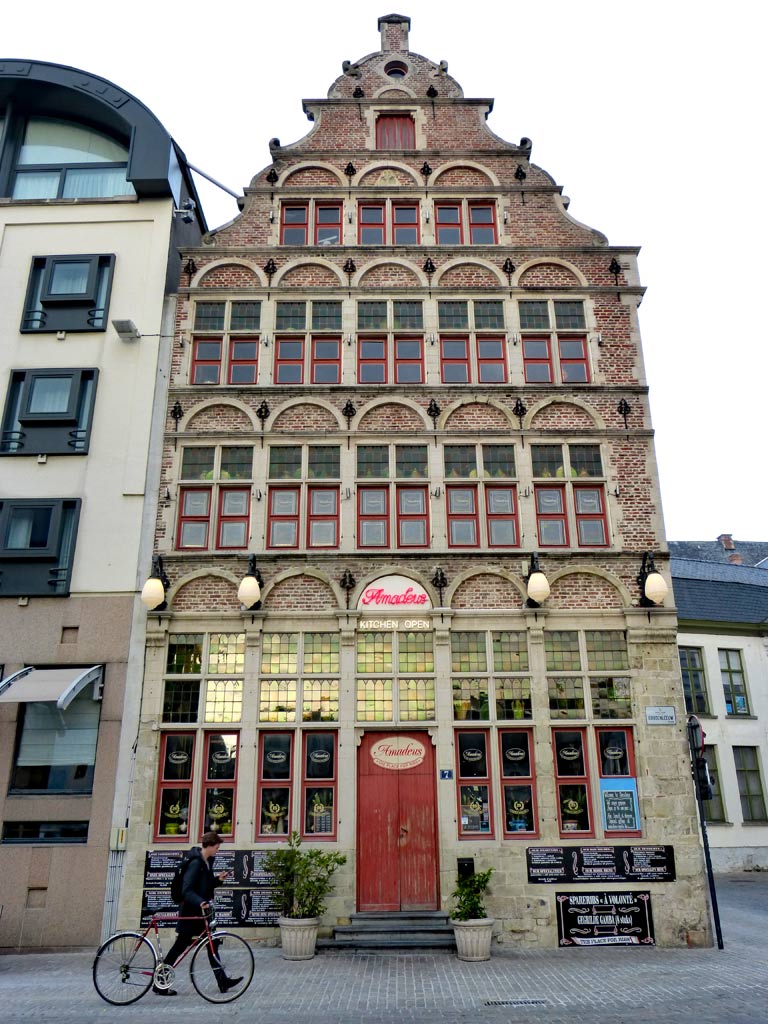 Fachwerkhaus mit roter Tür in Gent mit vorbeilaufendem Fahrradfahrer, Gent Sehenswürdigkeiten, Moments of Travel