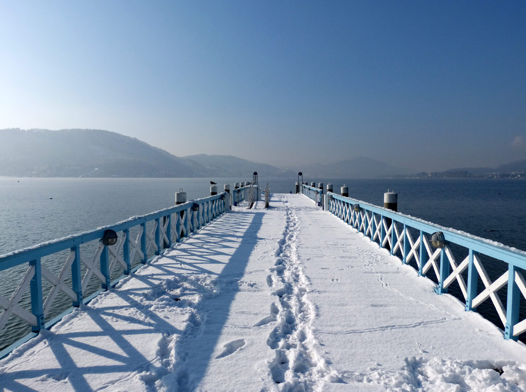 steg mit schnee am ossiacher see