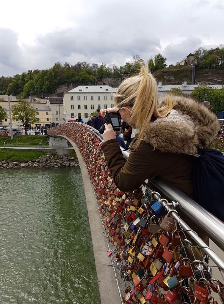 Frau fotografiert Liebesschlösser Brücke in Salzburg