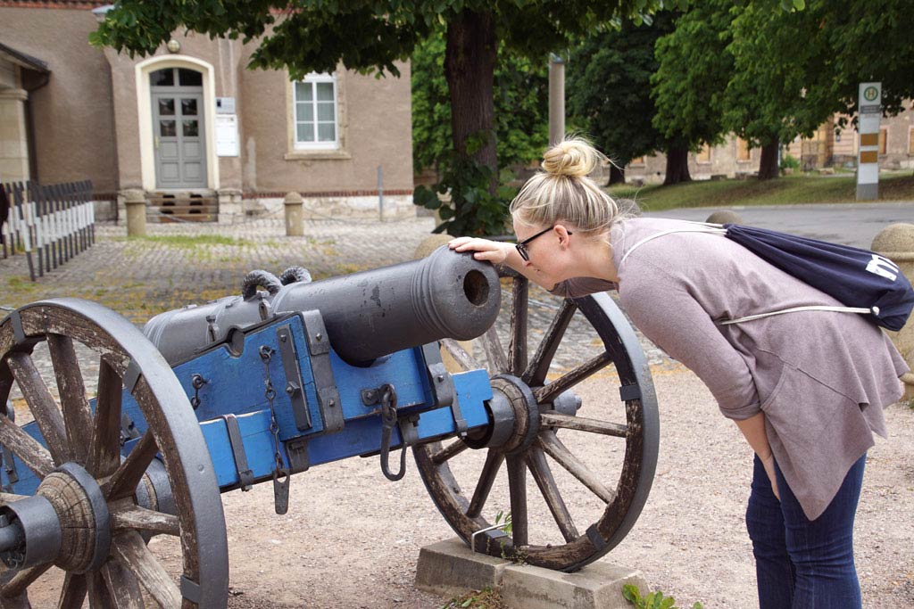 Frau guckt in Kanonenrohr